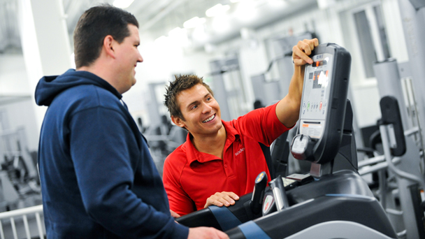 a personal trainer showing something to a man in a gym