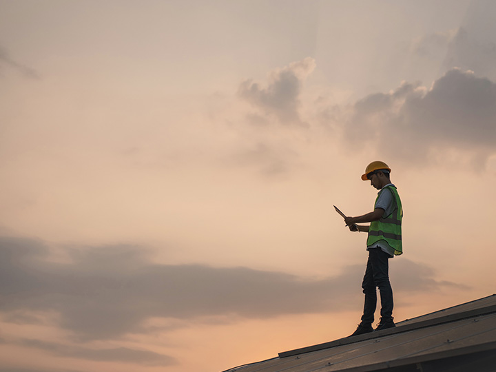 Engineer on a roof reviewing document