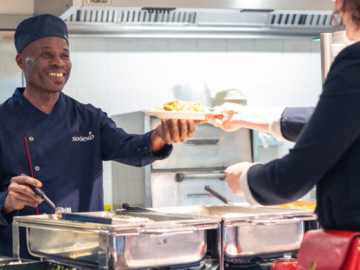 Man in uniform smiling delivering plate of food