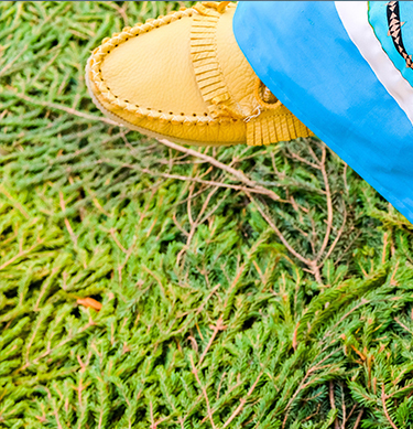 A person standing, wearing bright yellow shoes, with a neutral background.