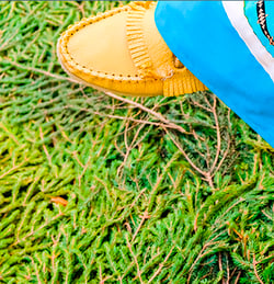 A person standing, wearing bright yellow shoes, with a neutral background.