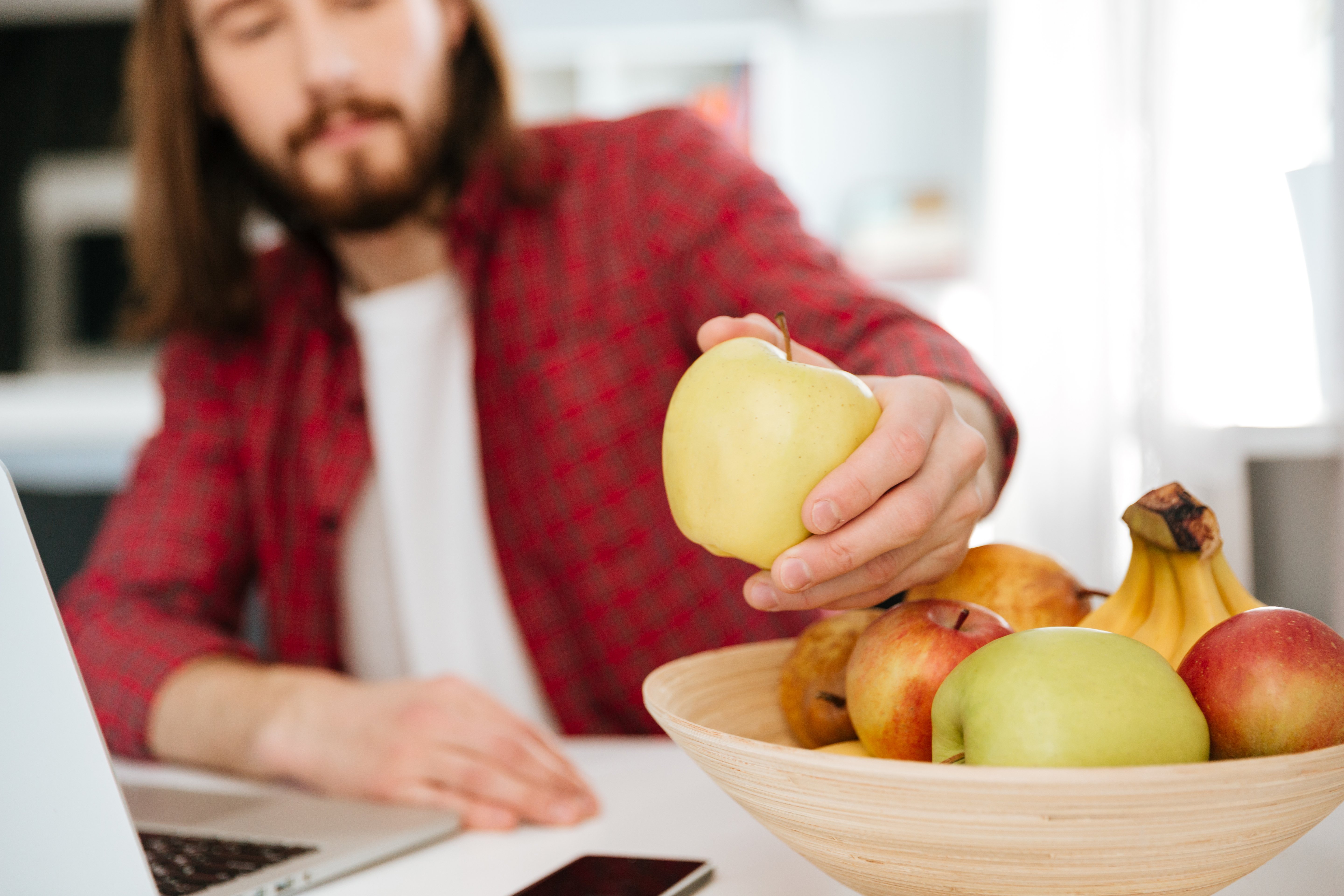 closeup-man-eating-fruits-using-laptop-home