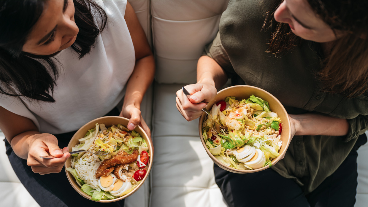 top view of two women sharing healthy food on a sofa