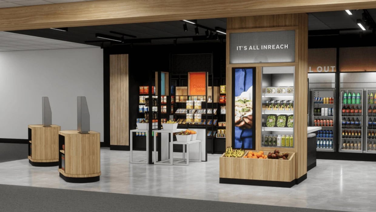 Modern store interior with wooden fixtures, shelves of packaged goods, fresh produce displays, and refrigerated drinks.