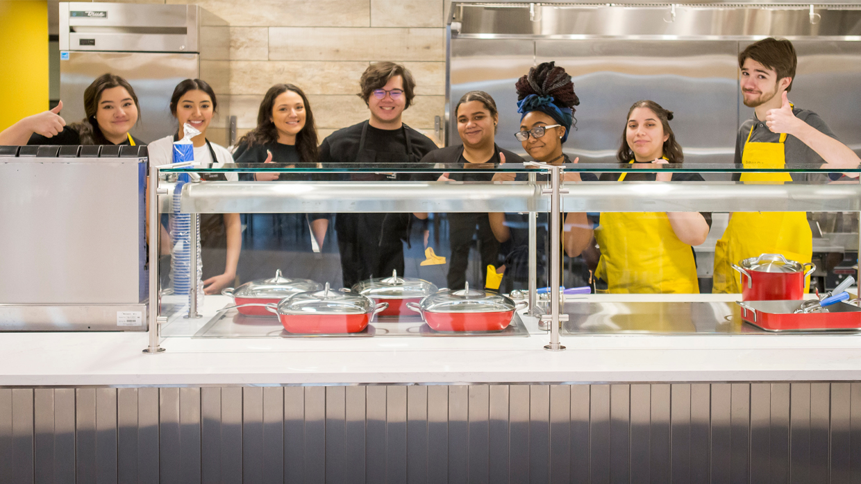 A diverse group of University of Northern Colorado students standing in a kitchen and smiling.