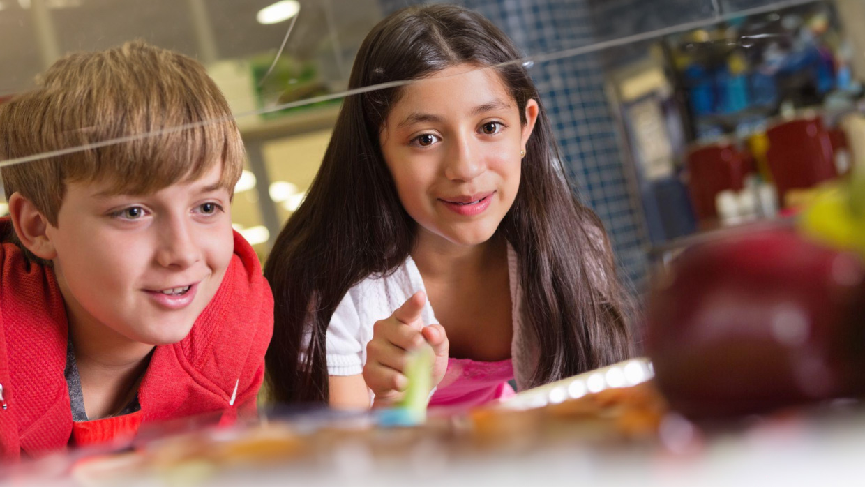 Two children intently observing a computer screen together, engaged in an activity or learning experience.