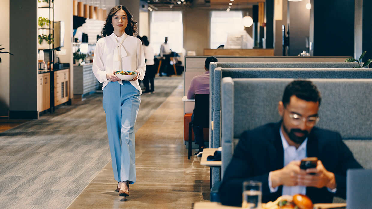A man eating in a booth while a women walks by in an upscale dining area