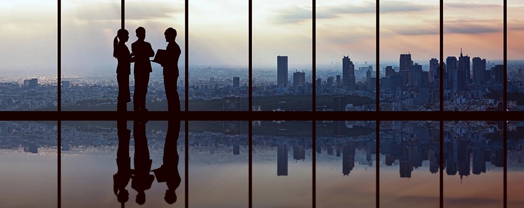 Silhouettes of business people standing against a glass wall, creating a professional and modern atmosphere.