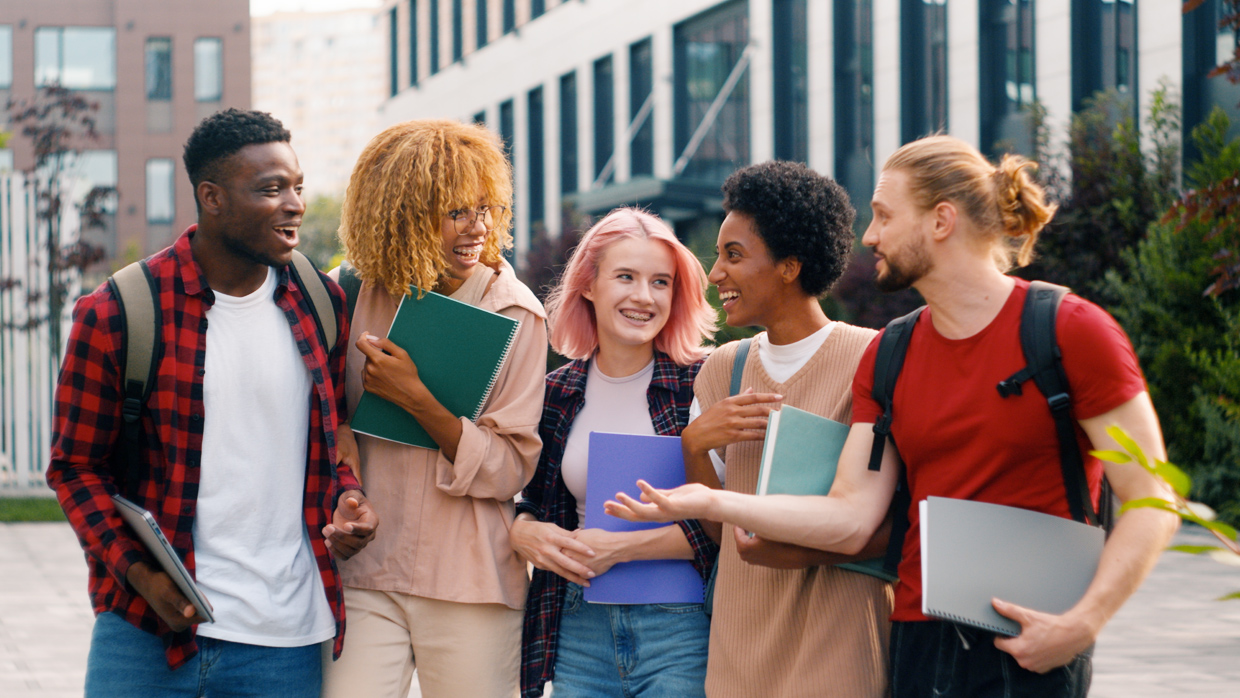 young people handling books and smiling