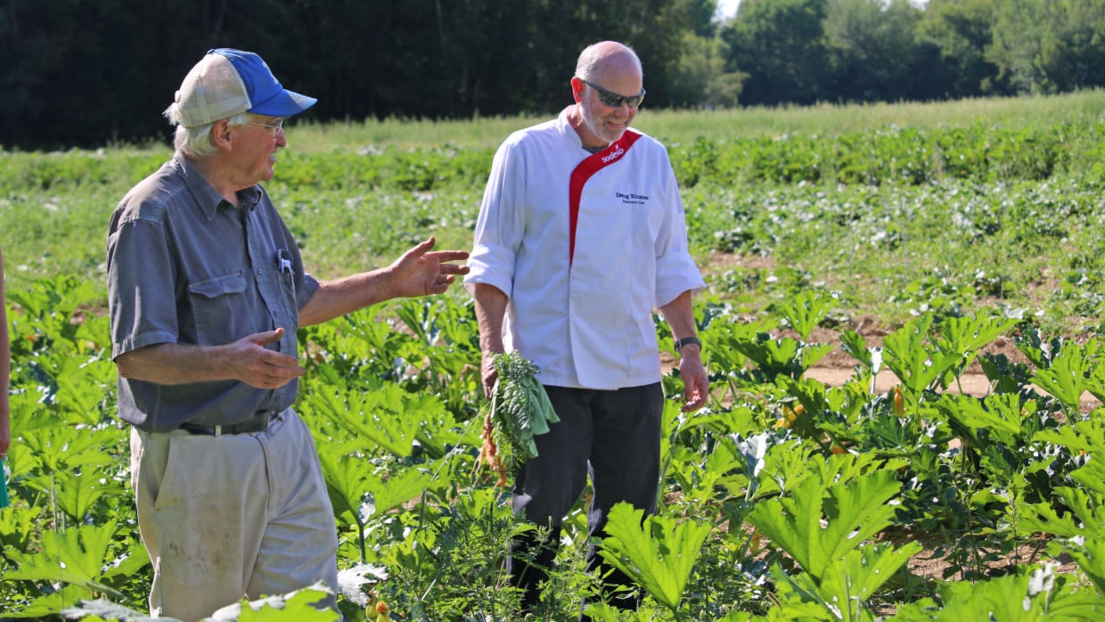 Sodexo chef walking through a local farm field in Maine during a visit
