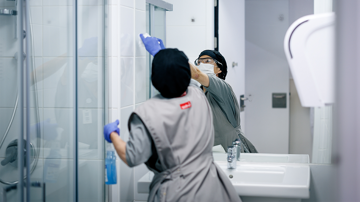 female staff cleaning a mirror