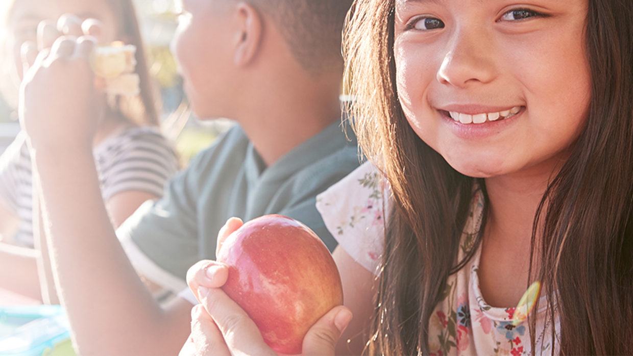 girl smiling with apple at school