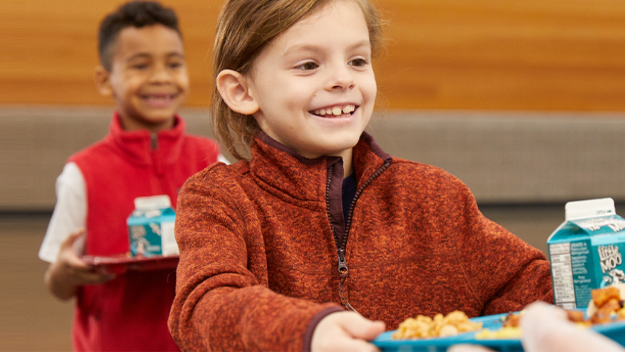 little girl smiling with food tray at school