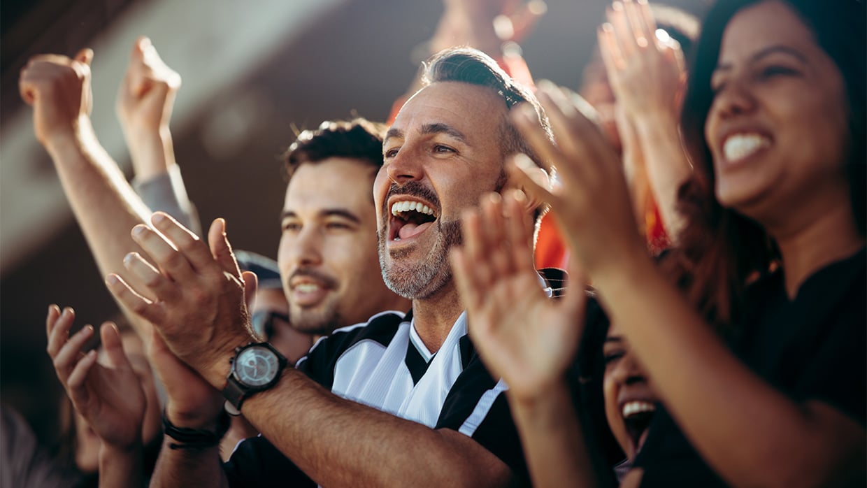 A diverse crowd cheering and clapping at a sporting event