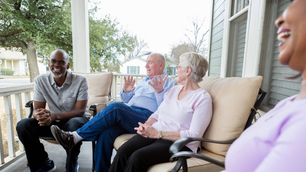 Group of seniors enjoying a conversation on a porch.>