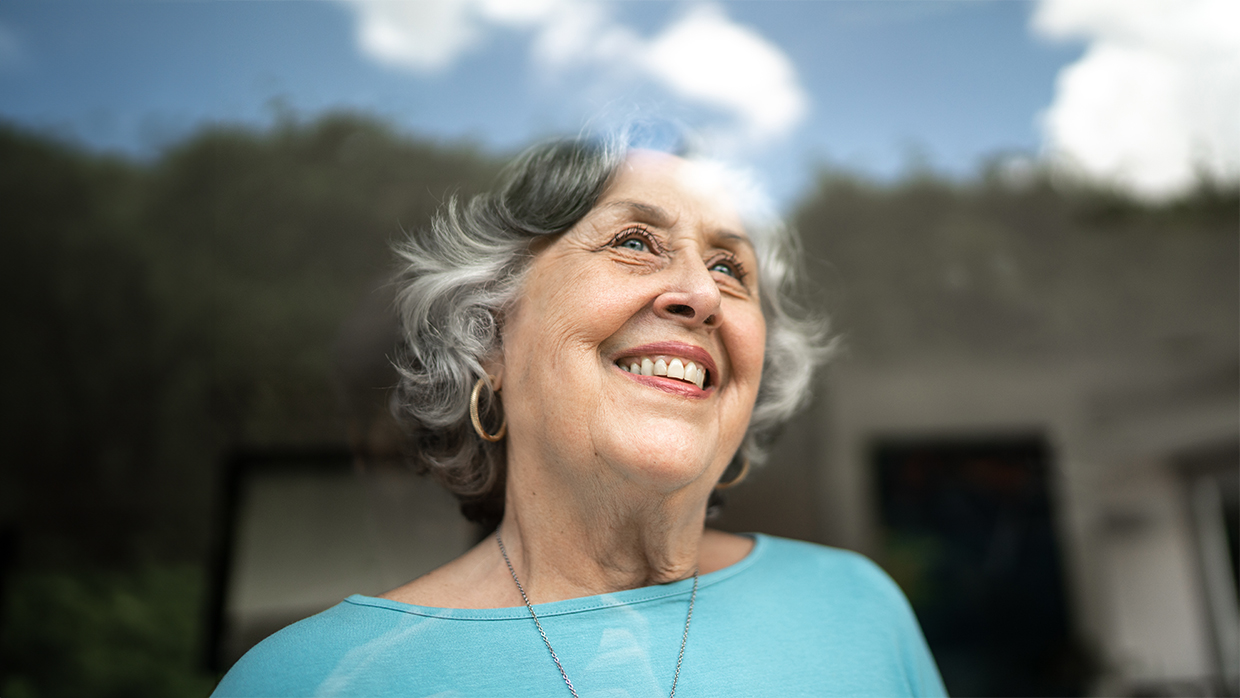 A smiling senior woman looking through a window