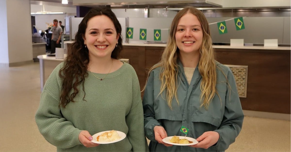 Two students smiling while holding a Brazilian dish during a Global Chef lunch at SUNY Oneonta.