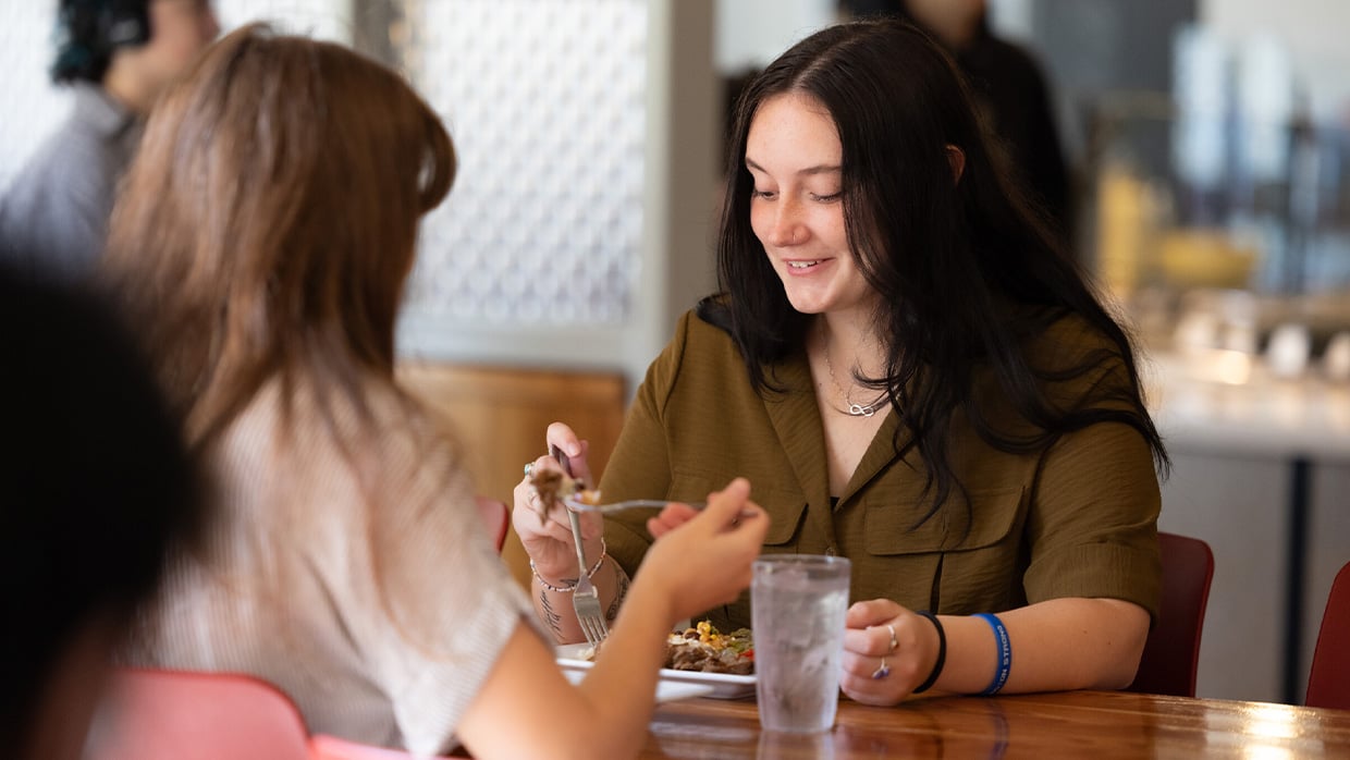 Two young women enjoying a meal in a cafeteria