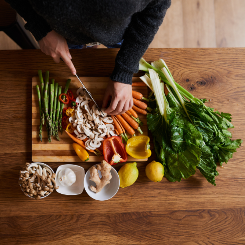 Top view of person cutting vegetables on a wooden board