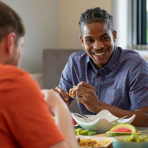 University student smiling and enjoying a meal with friends.