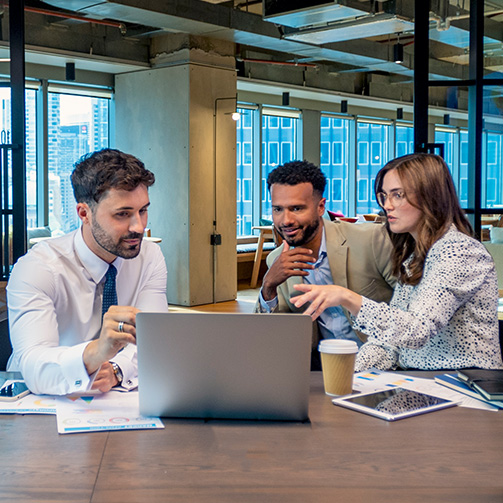 three workers looking a laptop