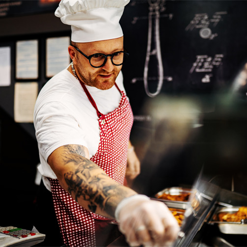 Chef wearing glasses and an apron working in the kitchen. 