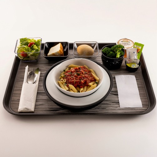 Top-down view of a Clinicia patient menu meal, featuring penne pasta marinara, a fresh side salad and a serving of broccoli on a hospital tray. 