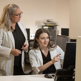 Two dietitians review patient information together at a computer.