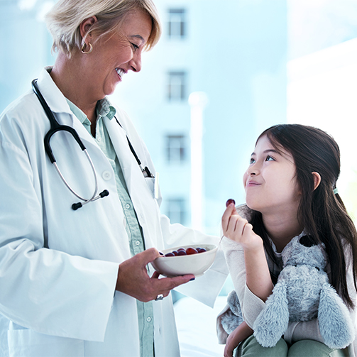 A doctor and a child patient both smiling together.