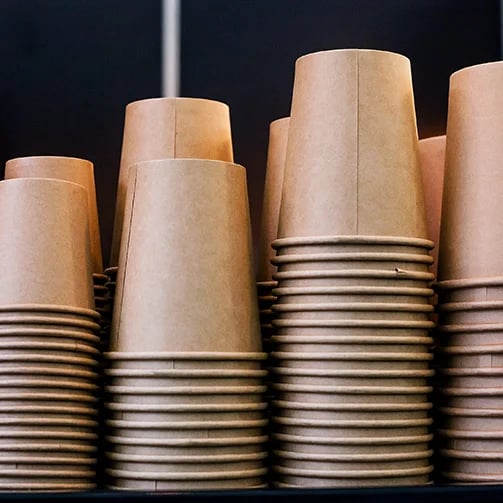 Stacked paper cups in a tower formation, showcasing various colors and designs, ready for use at an event or gathering.