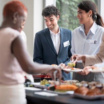 Professionals interact and serve themselves from a buffet during an industry networking event.
