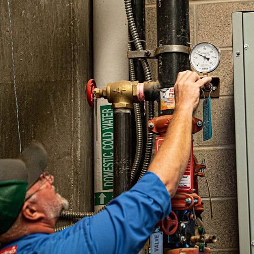  A Sodexo technician adjusts a pressure gauge in a utility room.