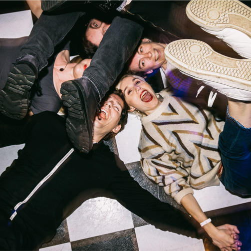 Friends holding hands and huddled in a circle on the floor, having fun.