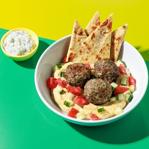 Bright Bites Kitchen Greek Meatball Hummus Bowl with cucumber, tomato and pita.