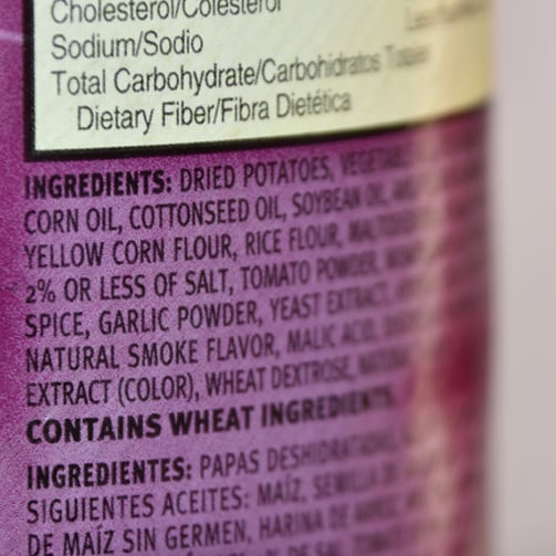 Close up of a packaged food ingredient label showing nutrition information and an ingredients list in English and Spanish, including allergen information highlighted within the text.