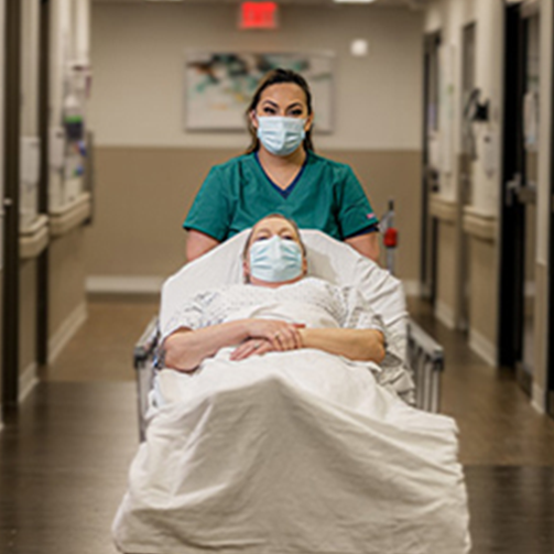 female staff pushing female patient in a bed