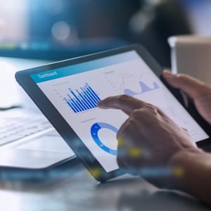 Close up of a HTM professional using a tablet displaying a real-time analytics dashboard. 