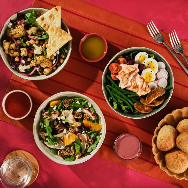 Overhead view of fresh salad bowls arranged on a colorful table layout.