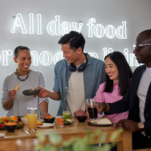 A group of diverse individuals gathered around a table, engaged in conversation and collaboration.