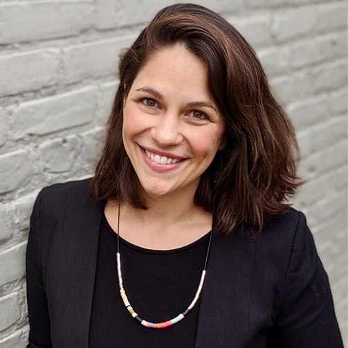 A woman in a black shirt and necklace poses, showcasing her outfit and accessories.