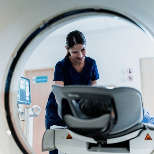 Healthcare professional assists a patient positioned inside a CT scanner.