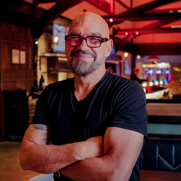 a man smiling with glasses an crossed arms