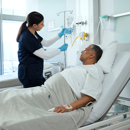 A nurse checking the IV drip connected to a patient in bed.