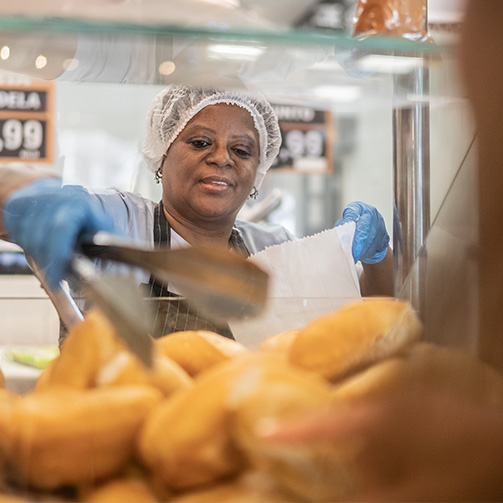 a woman taking a bread from a stand