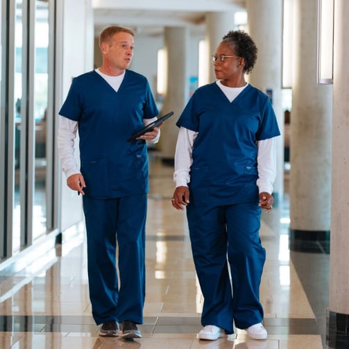 Two hospital employees walking down a hallway together.