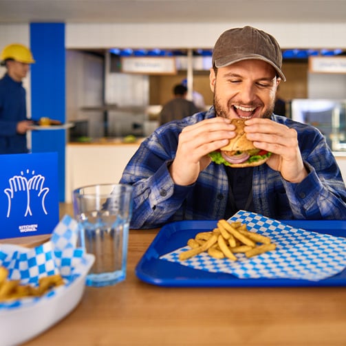 A happy customer sitting at a table enjoying a sandwich with fries on his plate