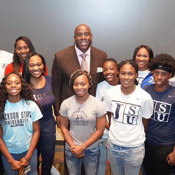 A group of people smiling and posing for a photo with a man in a casual setting.