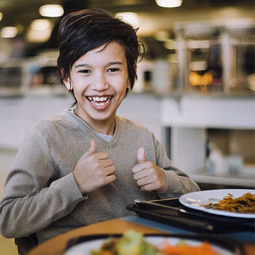 Student at lunch giving two thumbs up, showing excitement.