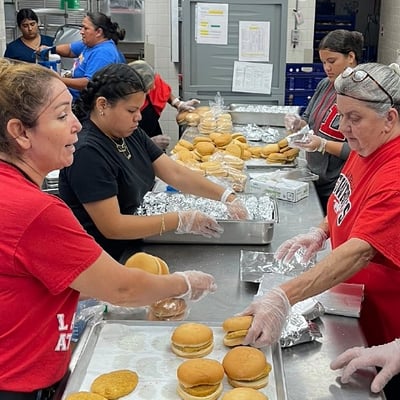 School dining staff assembling meals in the kitchen for summer meal distribution.
