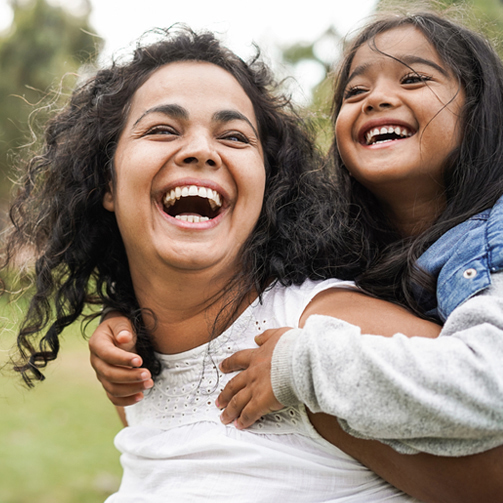 Two individuals outdoors, one giving a piggyback ride on a grassy area.